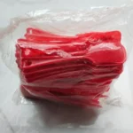 Side view of sealed red disposable plastic spoon pack