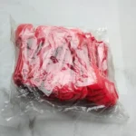 Angled view of red disposable plastic spoons in transparent packaging